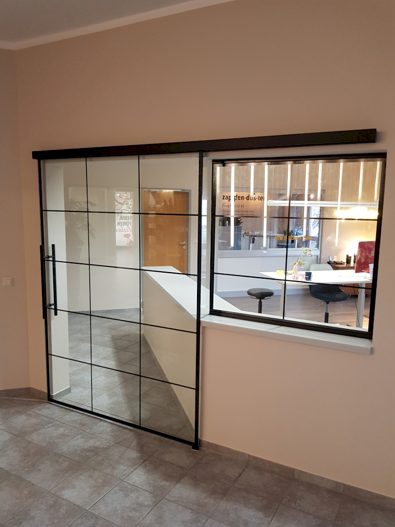 Einzigartige Schiebetüre mit feststehendem Seitenteil. Ganzglasschiebetüre mit Digitaldruck. Griff und Beschlag in schwarz matt.