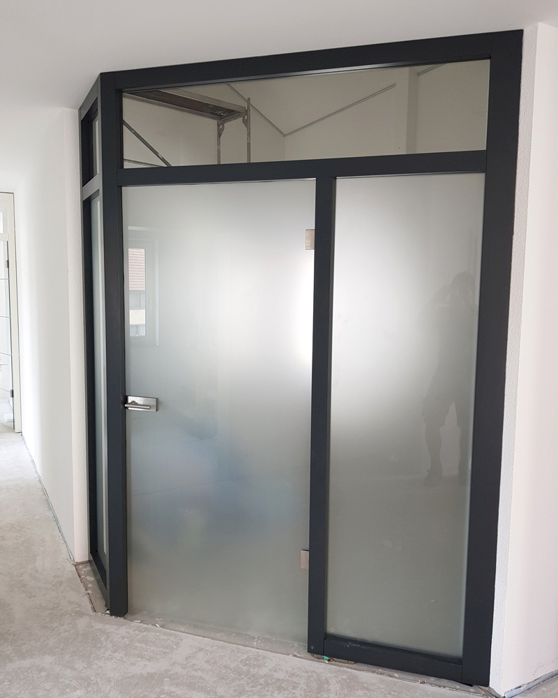 Windfangelement über Eck in anthrazitgrau lackiert. Glas in Satinato. Oberlichter in Klarglas.